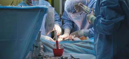 Team of surgery doctors operating a patient in surgical room. Healthcare and medical aid concept