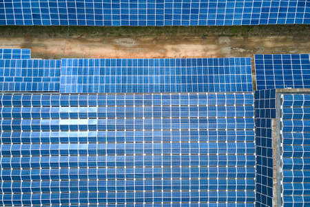 Aerial view of solar power plant with blue photovoltaic panels mounted on industrial building roof...