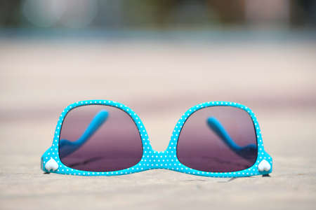 Closeup of blue sunglasses on swimming pool side on warm sunny day. Summer vacation conceptの写真素材