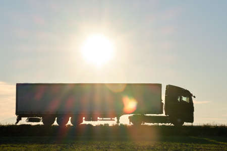 Semi-truck with cargo trailer driving on highway hauling goods in evening. Delivery transportation and logistics conceptの写真素材