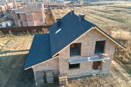 Aerial view of house roof top covered with ceramic shingles. Tiled covering of building under constructionの写真素材