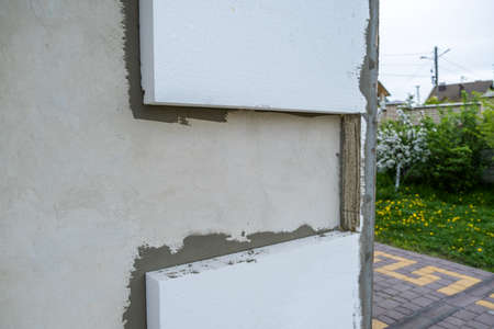 Installation of styrofoam insulation sheets on house facade wall for thermal protectionの写真素材