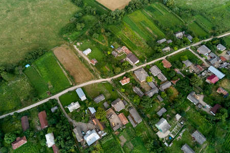 Aerial landscape view of village houses and distant green cultivated agricultural fields with...