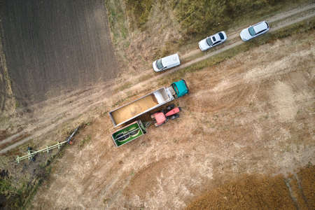 Aerial view of cargo truck driving on dirt road between agricultural wheat fields making lot of dust. Transportation of grain after being harvested by combine harvester during harvesting seasonの写真素材