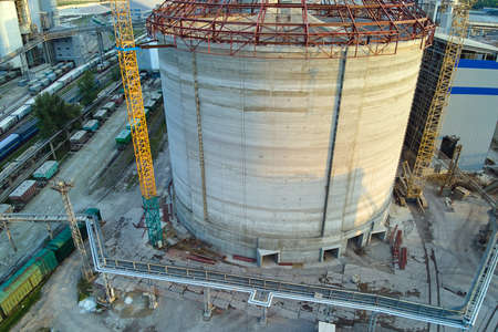 Aerial view of cement factory under construction with high concrete plant structure and tower cranes at industrial production area. Manufacture and global industry conceptの写真素材