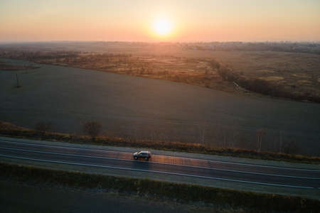 Aerial view of intercity road with blurred fast driving car at sunset. Top view from drone of highway traffic in eveningの写真素材