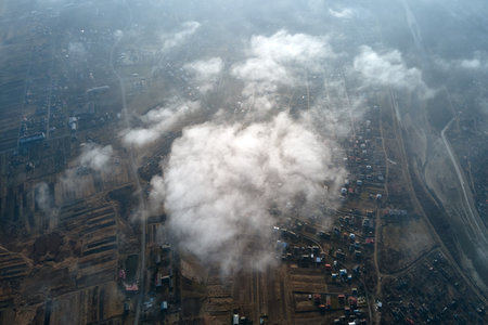 Aerial view from high altitude of distant city covered with puffy cumulus clouds forming before rainstorm. Airplane point of view of cloudy landscapeの写真素材