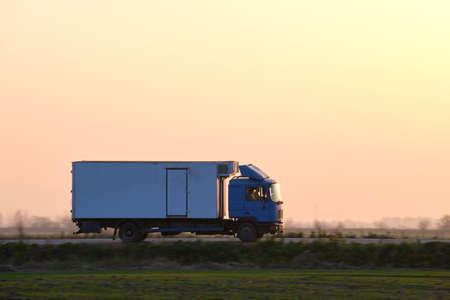 Cargo truck driving on highway hauling goods in evening. Delivery transportation and logistics...