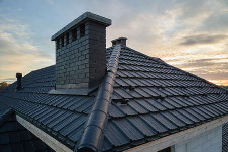 Snow guard for safety in winter on house roof top covered with ceramic shingles. Tiled covering of...