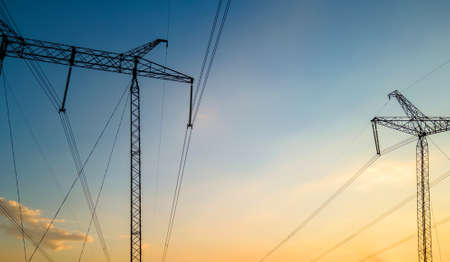 Dark silhouette of high voltage towers with electric power lines at sunriseの写真素材