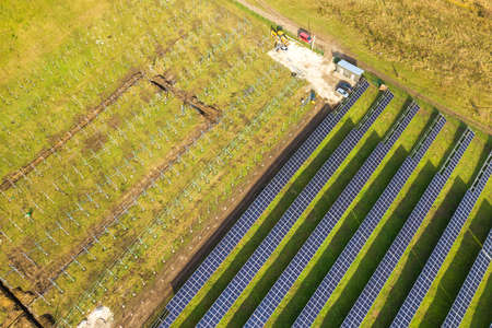 Aerial view of solar power plant under construction on green field. Assembling of electric panels...