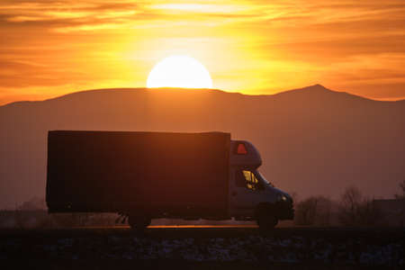 Cargo truck driving on highway hauling goods in evening. Delivery transportation and logistics conceptの写真素材