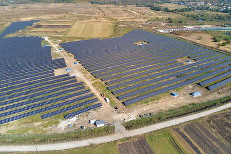 Aerial view of big sustainable electric power plant with many rows of solar photovoltaic panels for...