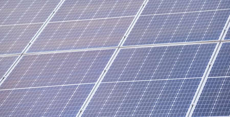 Closeup of building roof with rows of blue solar photovoltaic panels for producing clean ecological...