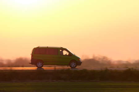 Passenger van driving fast on intercity road at sunset. Highway traffic in eveningの写真素材