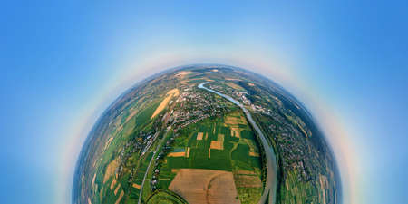 Aerial view from high altitude of little planet earth with small village houses and distant green...