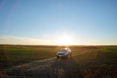 Aerial view of car driving on dirt road at sunset. Traveling by vehicle concept