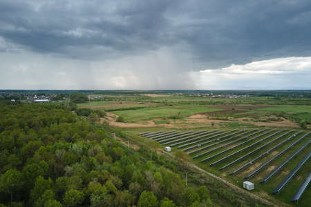 Aerial view of solar power plant on green field. Electric farm with panels for producing clean...