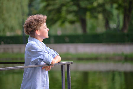 Young happy child boy relaxing in summer park. Positive kid enjoying summertime outdoors. Child wellbeing conceptの写真素材