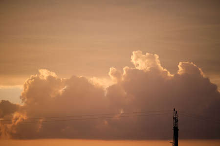Bright colorful sunset sky with vivid smooth clouds illuminated with setting sun light spreading to...
