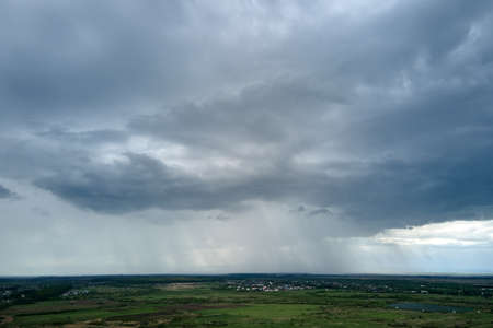 Landscape of dark clouds forming on stormy sky during thunderstorm over rural area