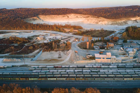 Aerial view of cargo train loaded with crushed stone materials at mining factory. Railway...