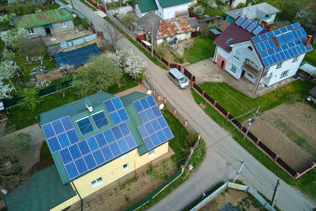 Residential house with rooftop covered with solar photovoltaic panels for producing of clean ecological electrical energy in suburban rural area. Concept of autonomous homeの写真素材