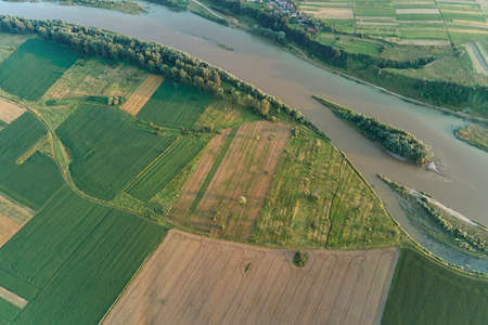 Aerial landscape view of village houses and distant green cultivated agricultural fields with...