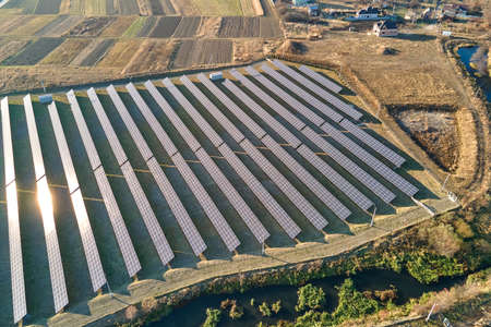Aerial view of large sustainable electrical power plant with rows of solar photovoltaic panels for...