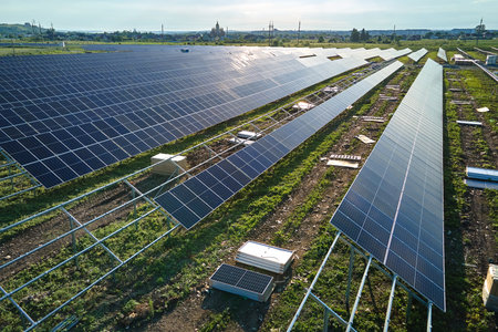 Aerial view of big electric power plant under construction with many rows of solar panels on metal...