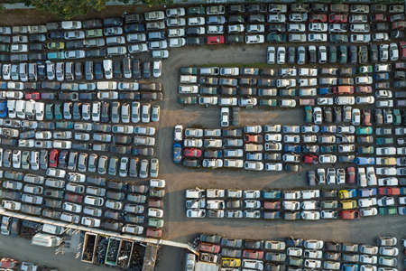 Aerial view of big parking lot of junkyard with rows of discarded broken cars. Recycling of old...