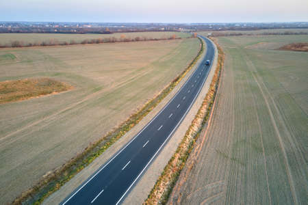 Aerial view of intercity road with blurred fast driving car at sunset. Top view from drone of...