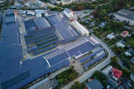 Aerial view of solar power plant with blue photovoltaic panels mounted on industrial building roof...