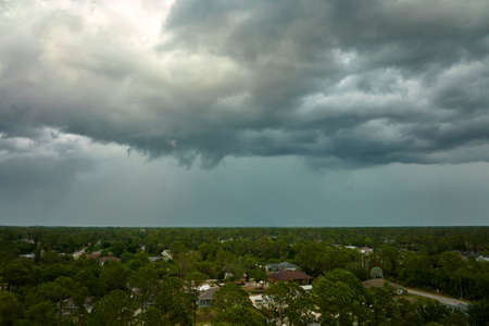 Dark stormy clouds forming on gloomy sky before heavy rainfall over suburban town area