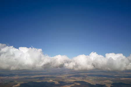 Aerial view from airplane window at high altitude of earth covered with puffy cumulus clouds forming...