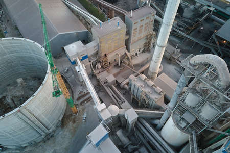 Aerial view of cement factory with high concrete plant structure and tower crane at industrial production site. Manufacture and global industry conceptの写真素材