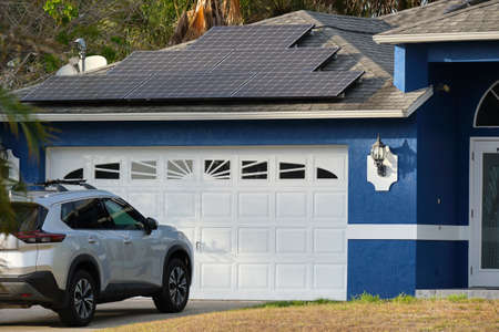 Car parked in front of wide garage double door on concrete driveway of new modern american houseの写真素材