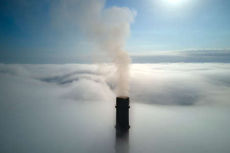 Coal power plant high pipes with black smoke moving upwards over clouds polluting atmosphere. Production of electrical energy with fossil fuel conceptの写真素材