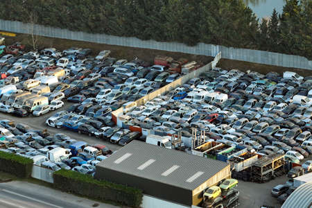 Aerial view of big parking lot of junkyard with rows of discarded broken cars. Recycling of old...
