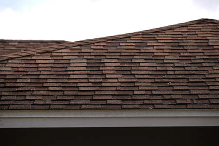 Closeup of house roof top covered with asphalt or bitumen shingles. Waterproofing of new building