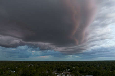 Dark stormy clouds forming on gloomy sky before heavy rainfall over suburban town area