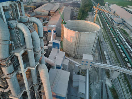 Aerial view of cement factory with high concrete plant structure and tower crane at industrial production site. Manufacture and global industry conceptの写真素材