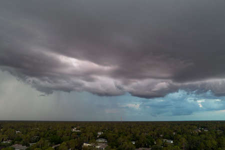 Landscape of dark ominous clouds forming on stormy sky before heavy thunderstorm over rural town...