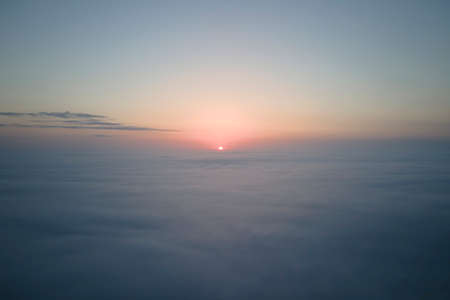 Aerial view from airplane window at high altitude of dense puffy cumulus clouds flying in eveningの写真素材