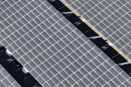 Aerial view of solar panels installed over parking lot with parked cars for effective generation of clean energyの写真素材
