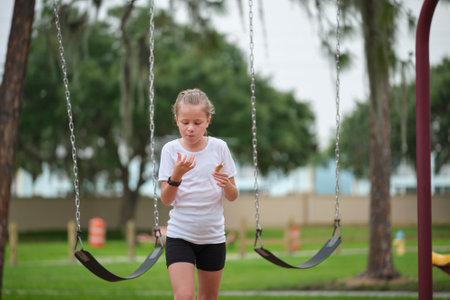 Young pretty excited teenage girl jumping out of the swings and running happily on summer sunny day. Recreation and vacation activitiesの写真素材