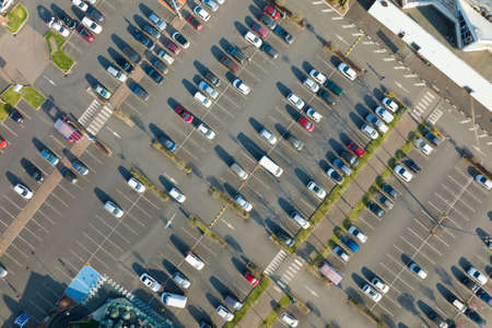Aerial view of many colorful cars parked on parking lot with lines and markings for parking places...