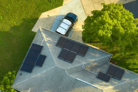 Residential house with rooftop covered with solar photovoltaic panels for producing of clean ecological electrical energy in suburban rural area. Concept of autonomous homeの写真素材