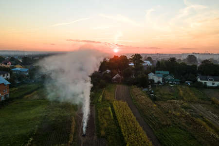 Aerial view of agricultural waste bonfires from dry grass and straw stubble burning with thick smoke polluting air during dry season on farmlandsの写真素材