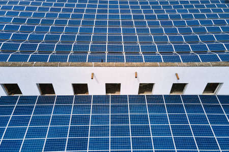Aerial view of blue photovoltaic solar panels mounted on industrial building roof for producing green ecological electricity. Production of sustainable energy conceptの写真素材